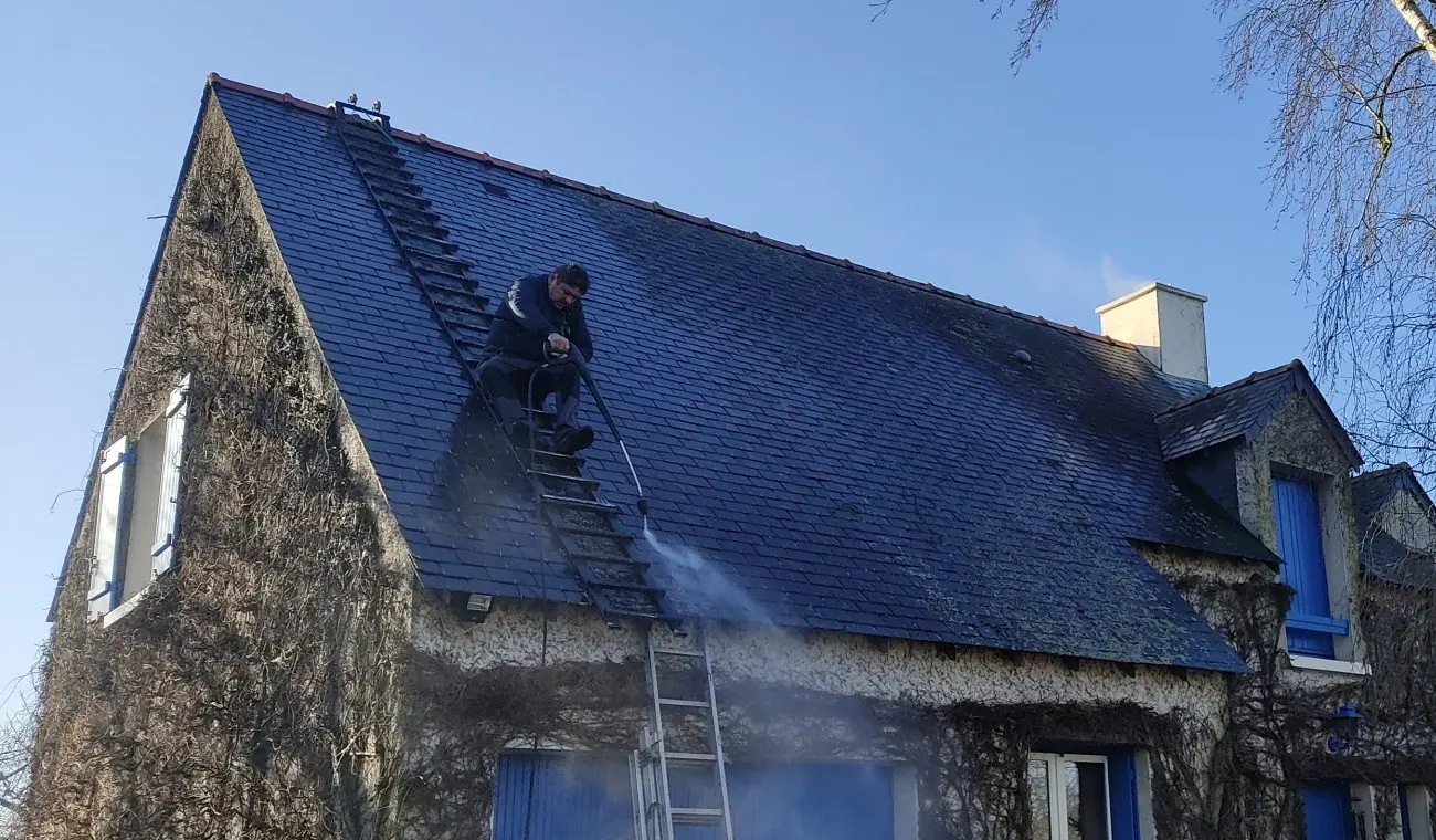 Samuel Martin sur un toit en ardoise, en plein démoussage
