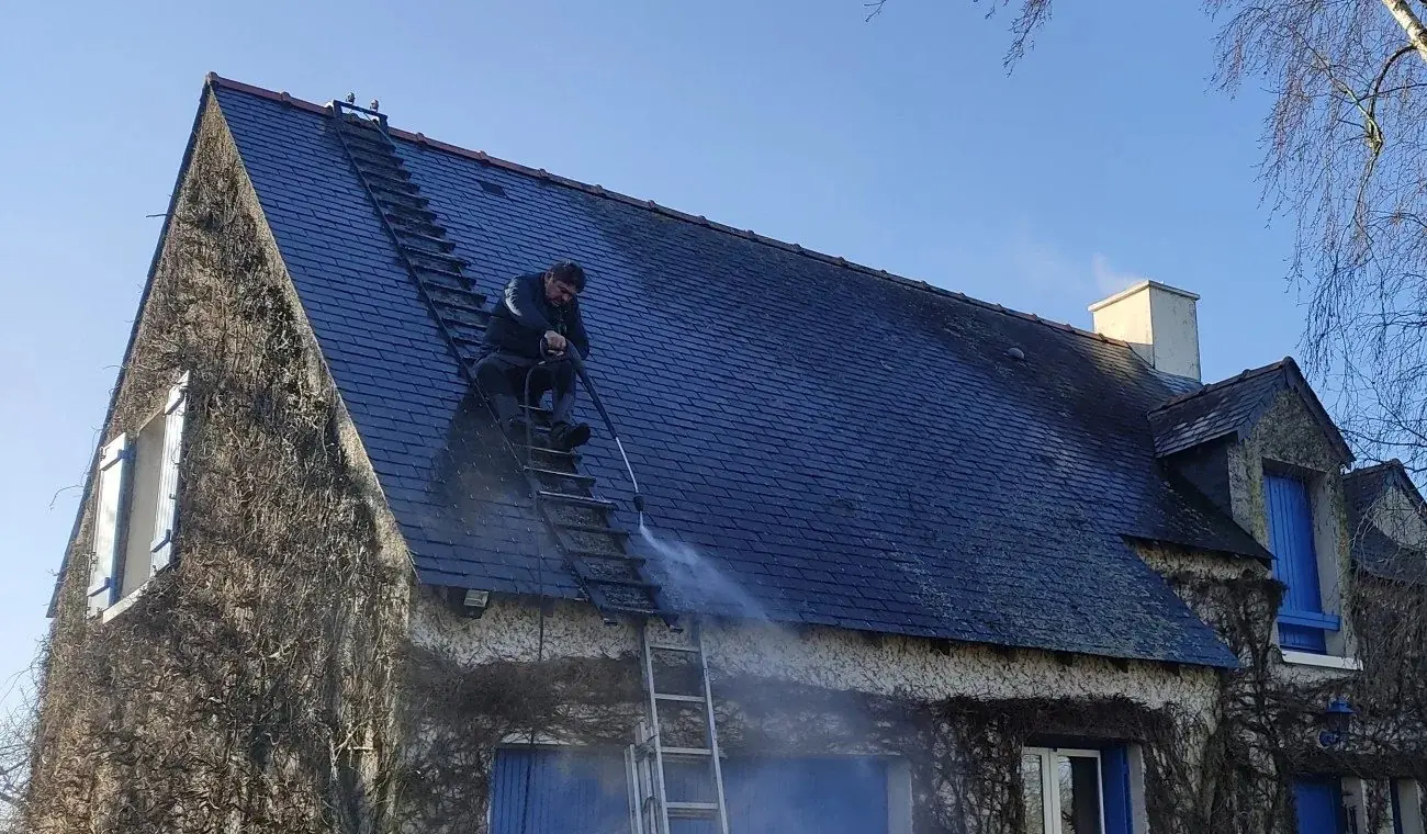 Samuel Martin en plein démoussage d'un toit en ardoise